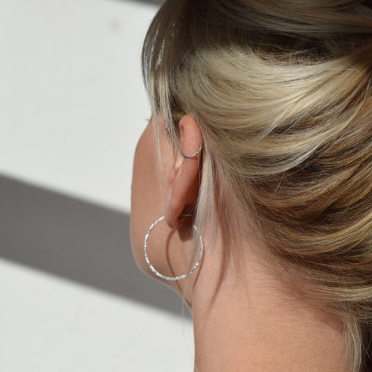 Photo taken from the back of model wearing silver mid sized hammered hoops