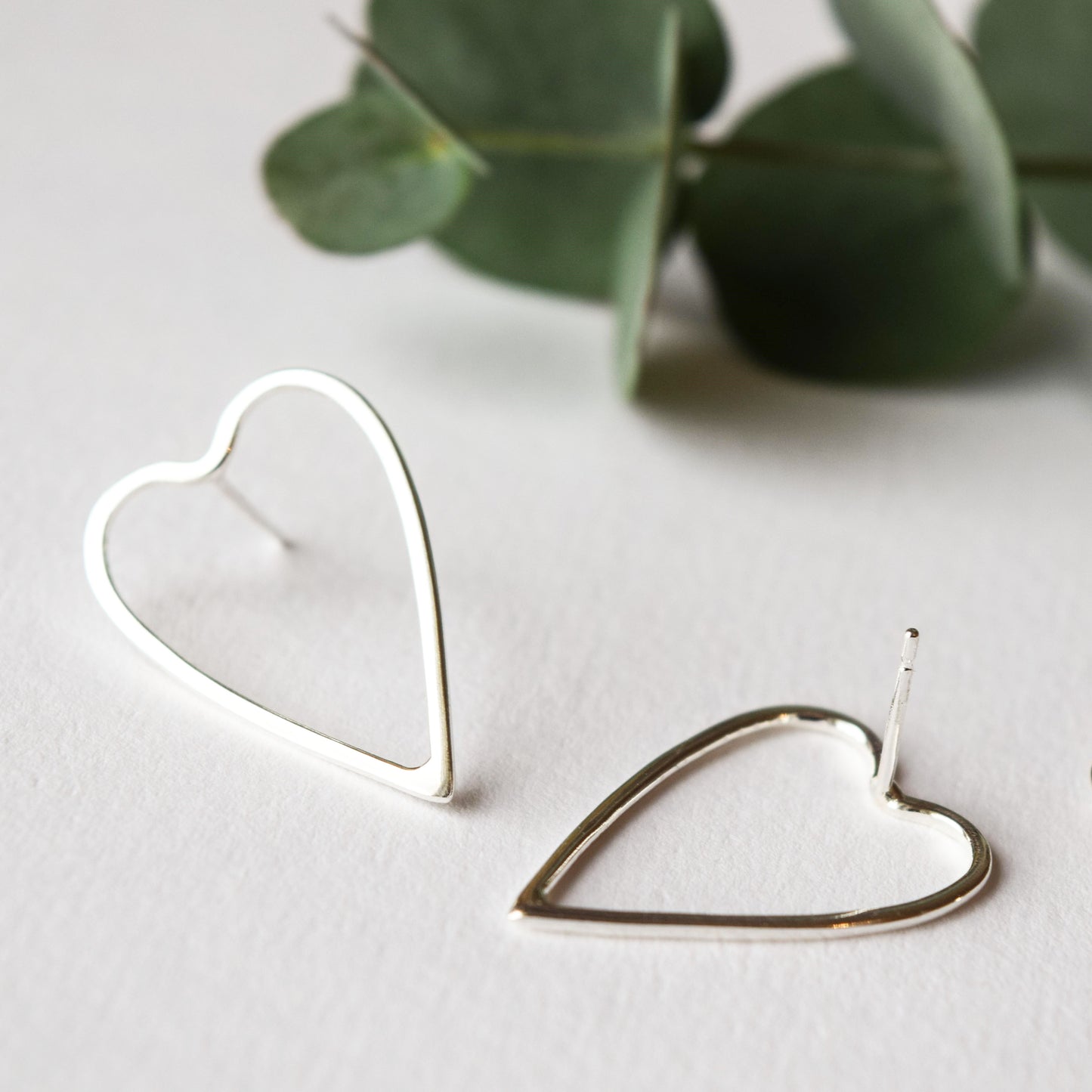 silver heart earrings close up on white background