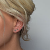 silver hammered bar stud worn alongside solid triangle studs