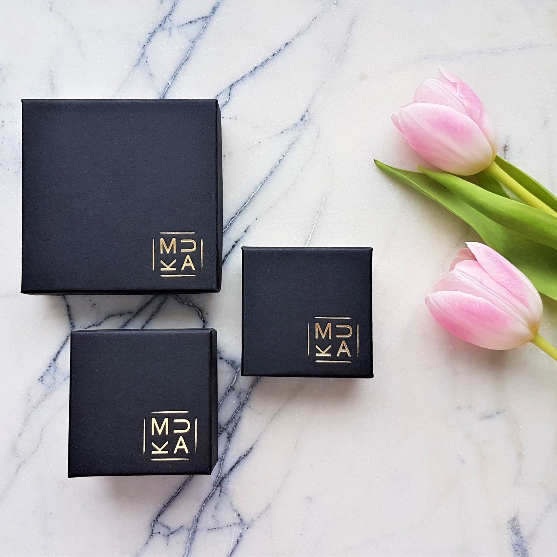 MUKA studio jewellery packaging boxes pictures next to pink tulip flowers