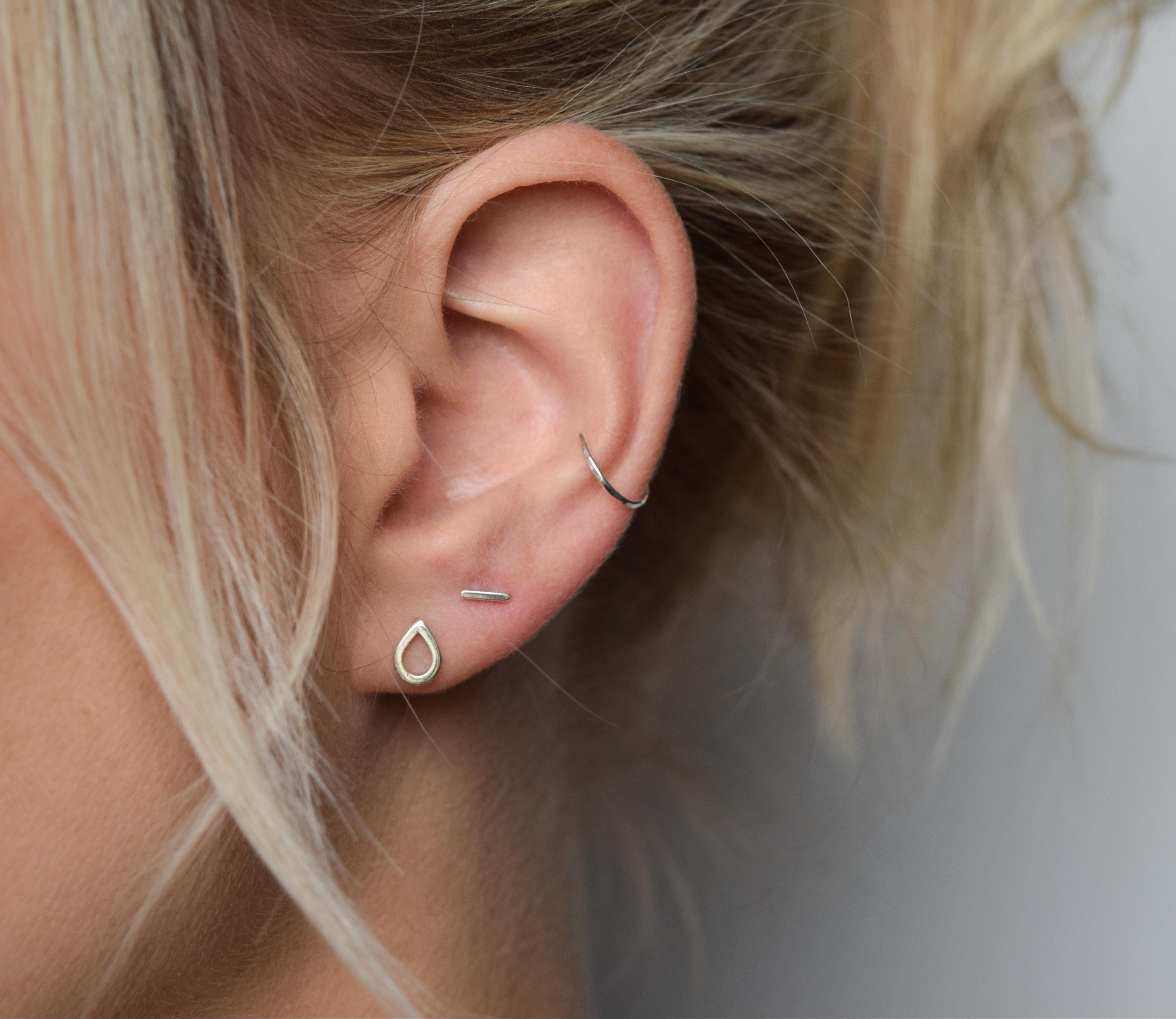 images shows silver teardrop stud  worn next to silver bar stud and silver conch cuff