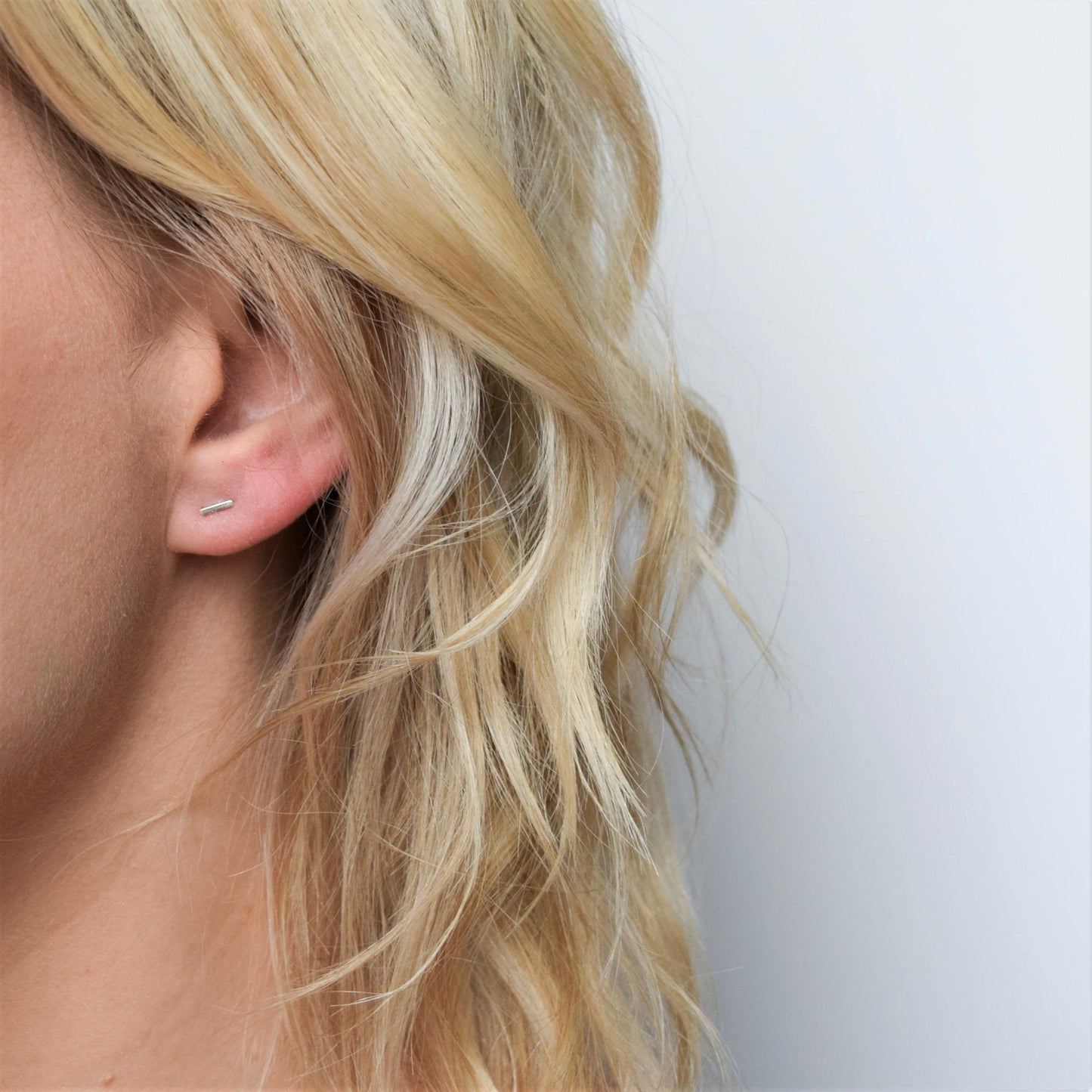 Handmade silver bar stud earrings worn by blond model