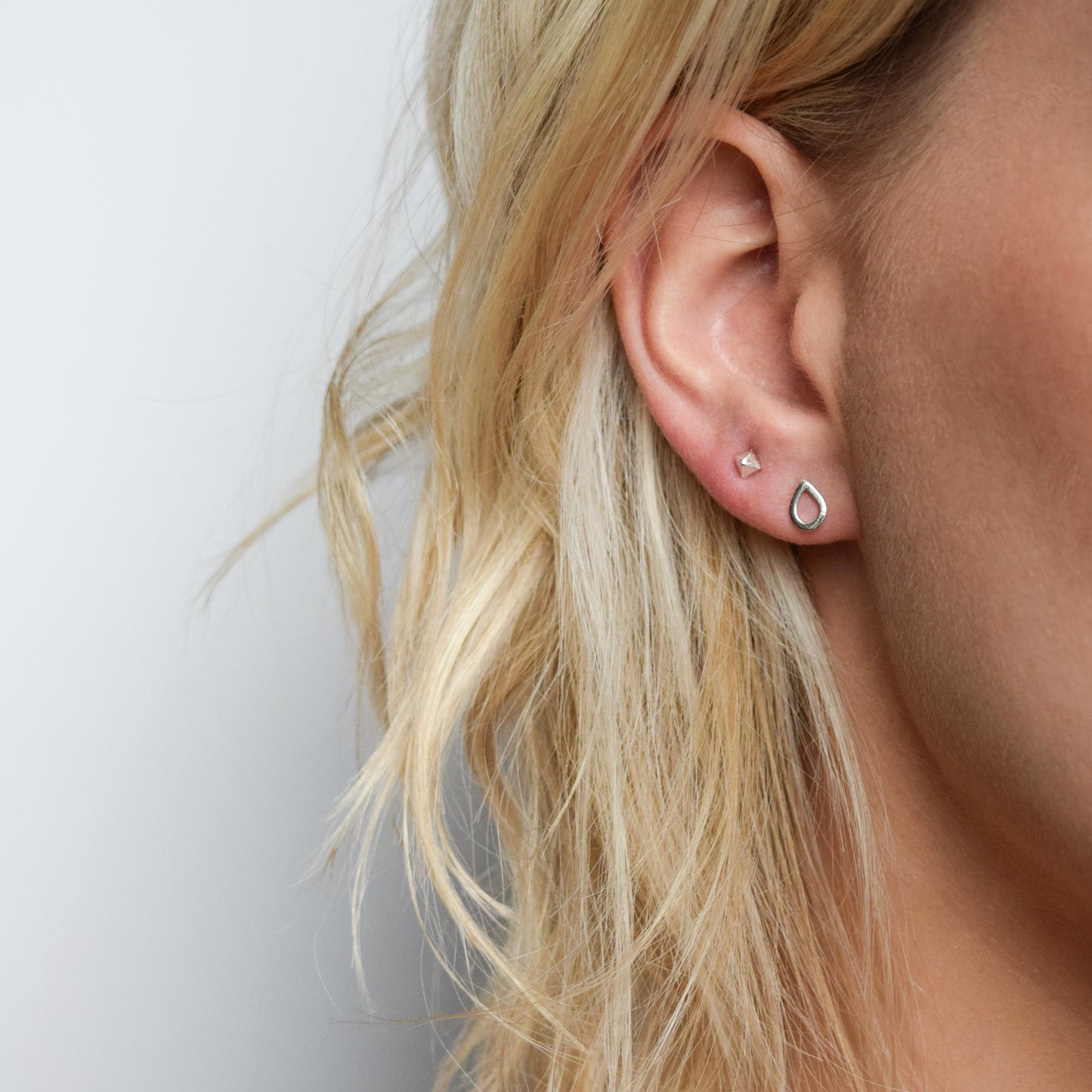 pyramid studs worn in the second piercing hole and teardrops studs in the first