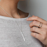 vertical bar necklace worn alongside cage ring